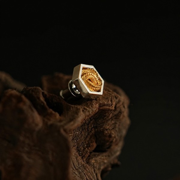 Close view of brass coiled-snake detail set into a sterling-silver hexagonal stud