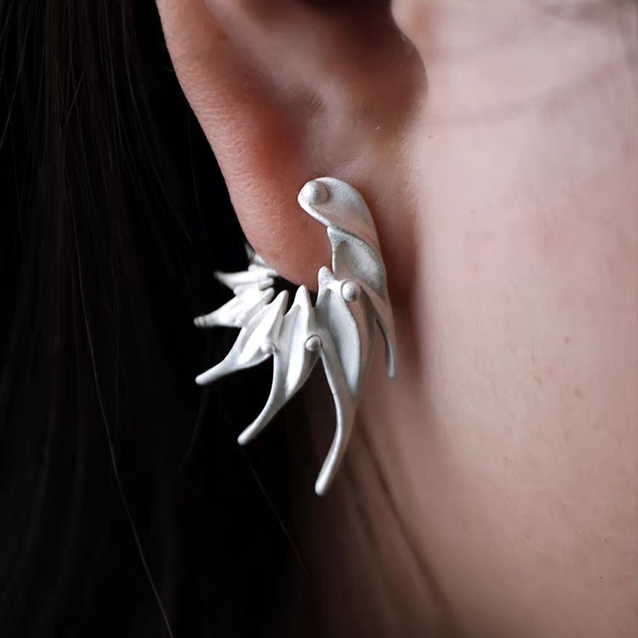 Directional silver bird ear climber worn upward along an earlobe